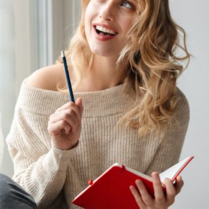 Optimistic young woman writing notes in notebook